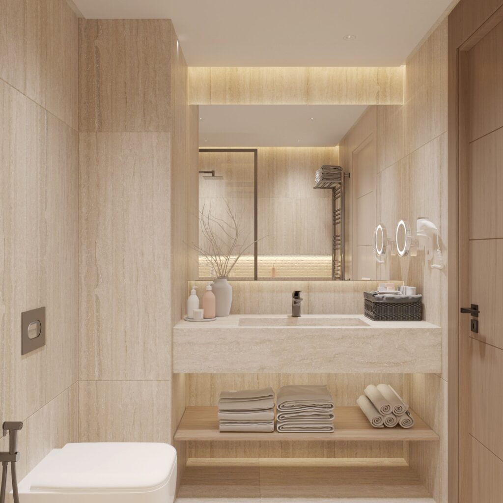 Hotel bathroom with stone finishes, integrated lighting, and organized towel storage.